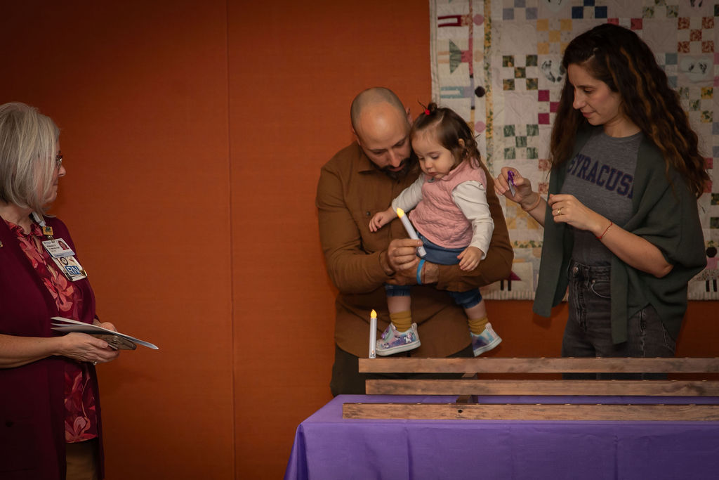 From left, outpatient bereavement coordinator Bernadette Flynn-Kelton watches as two adults and a small child add a candle to the row